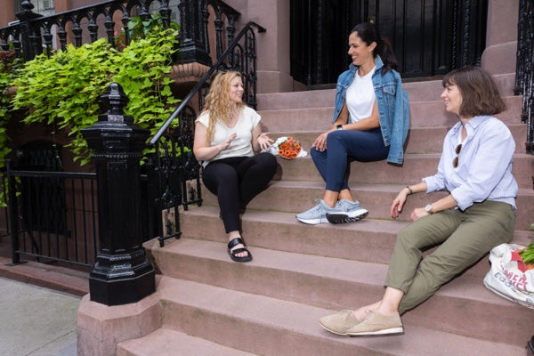 Three women on a stoop in NYC chatting, each wearing one of our pants in a different style.