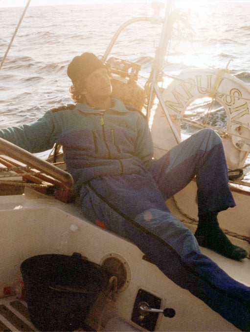 Stefan at 20 sitting on a sailboat backlit by a setting sun