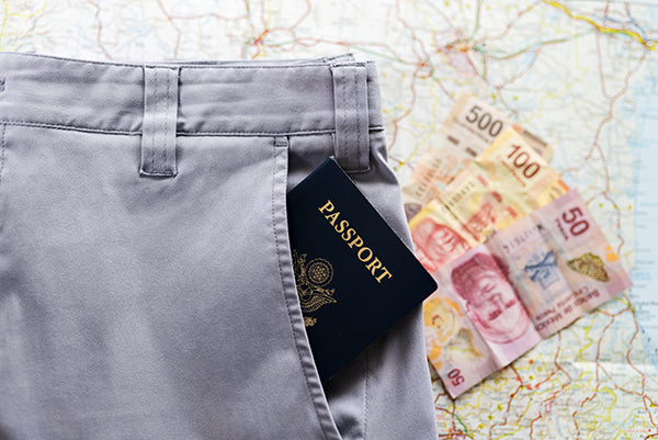 Chinos with a passport in a zippered security pocket, a map of Mexico, and foreign currency.