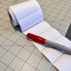 Roll of white adhesive labes with a red pen