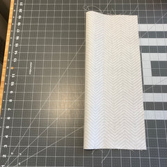 Folded fabric lengthwise sitting on a quilting cutting mat