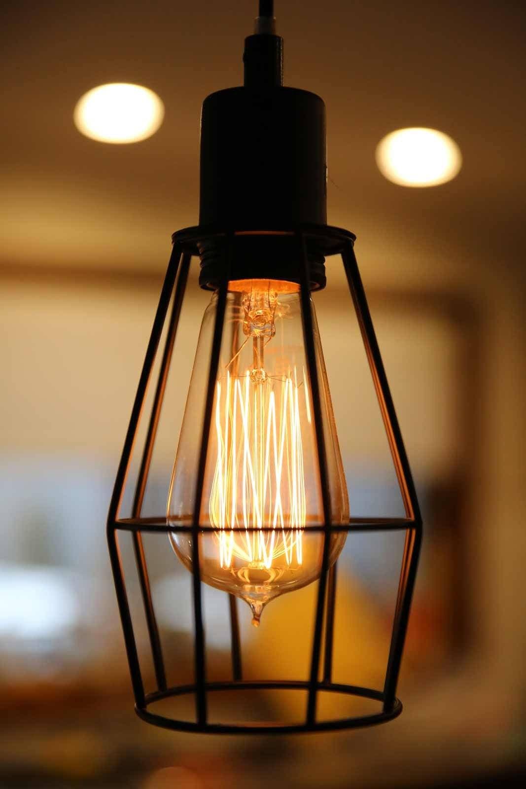 black wire cage pendant light hanging over a kitchen bench