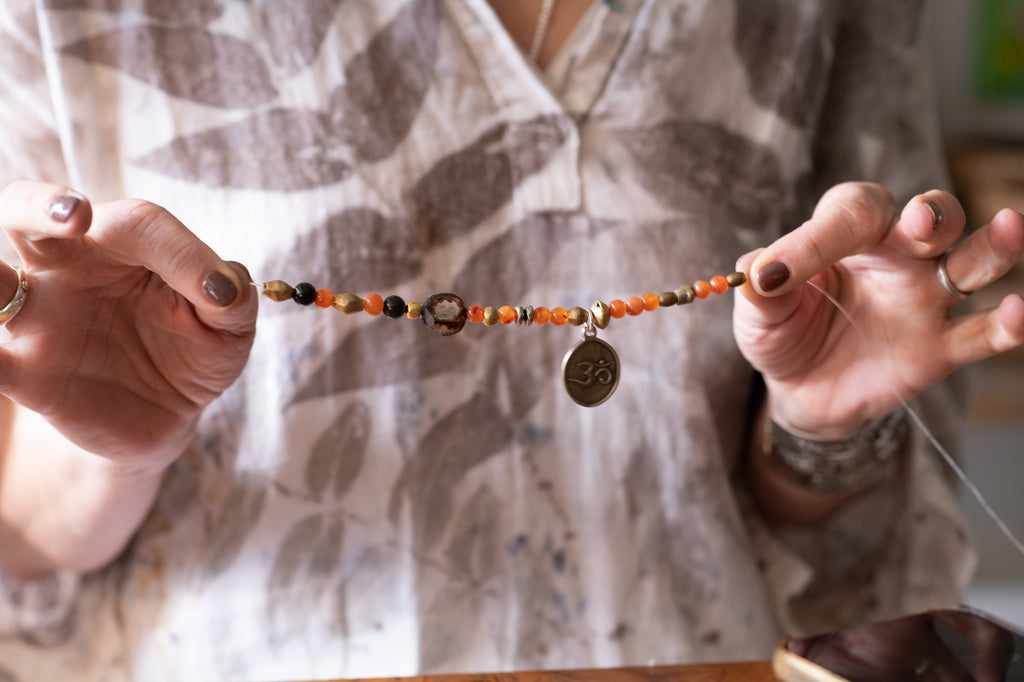 Two hands showing a string of beads with a charm