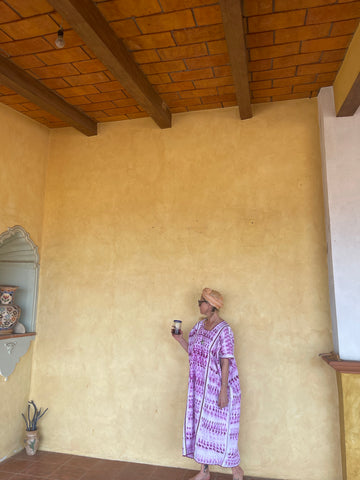 Lady in pink mexican dress against yellow wall