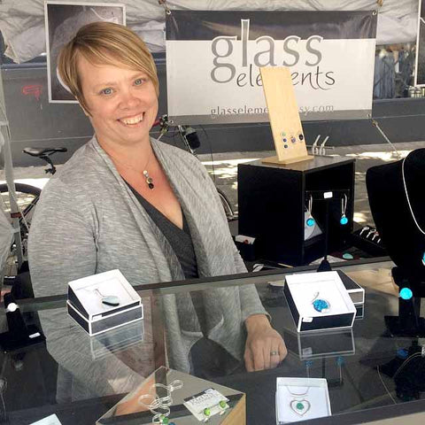 Artist Marja Huhta in her Glass Elements booth at an art show