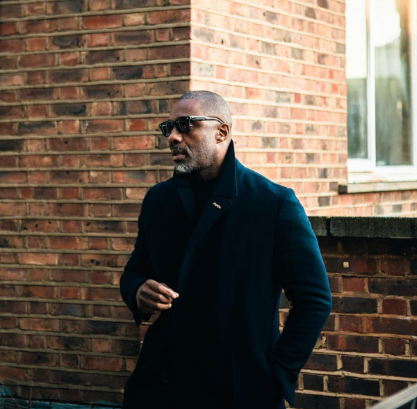 Idris Elba wearing a dark coat and shades.