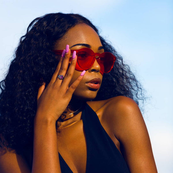 Black girl wearing red glasses and holding her face.