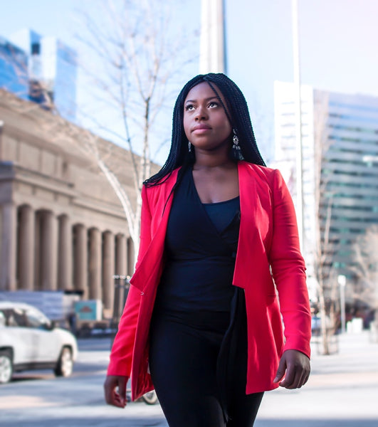 Black girl boss in a red jacket on the street.