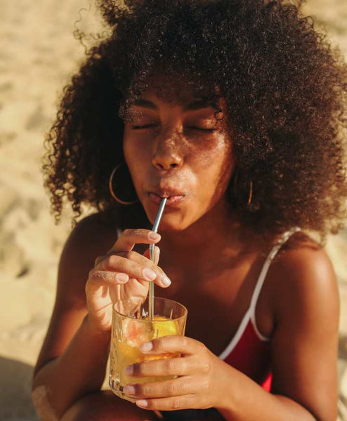 Girl sipping a refreshing drink while at the beach.