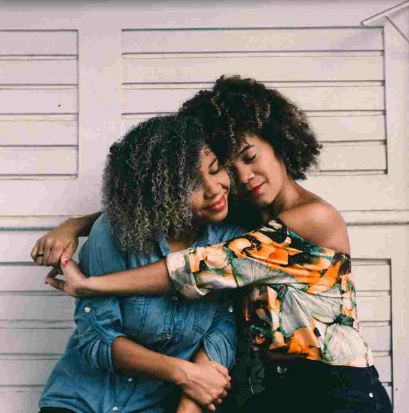 Two black girls hugging.