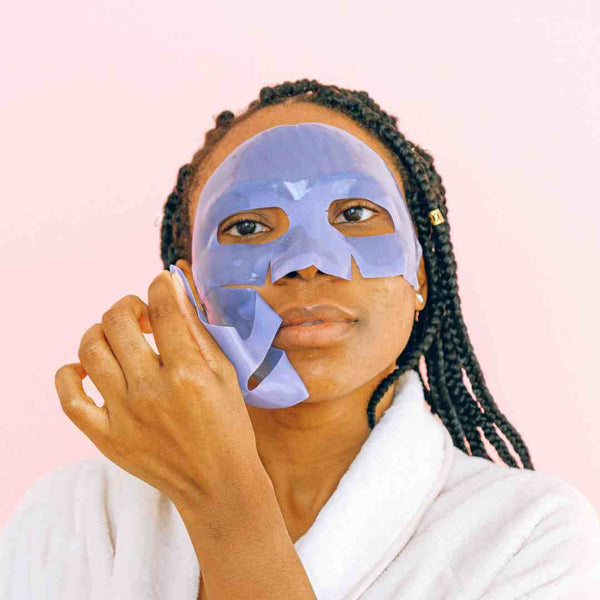 Black woman in a bathrobe with a facial mask on.