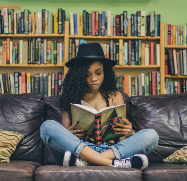 Girl reading a book while sitting on a sofa.
