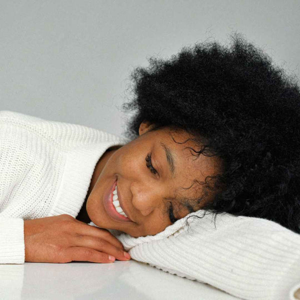 Black girl resting on her arm with her eyes closed.