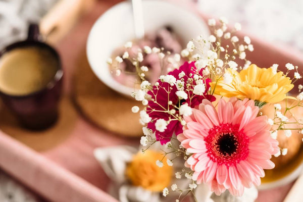 Breakfast in bed served on a tray with flowers.