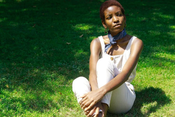 Black woman sitting on a grass and thinking.