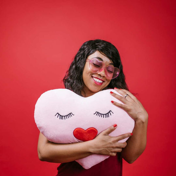 Black girl hugging a heart-shaped pillow.