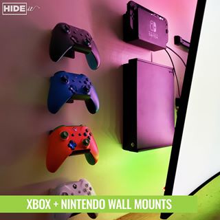 Xbox console and controllers plus Nintendo Switch wall mounted using HIDEit Mounts behind wall-mounted TV