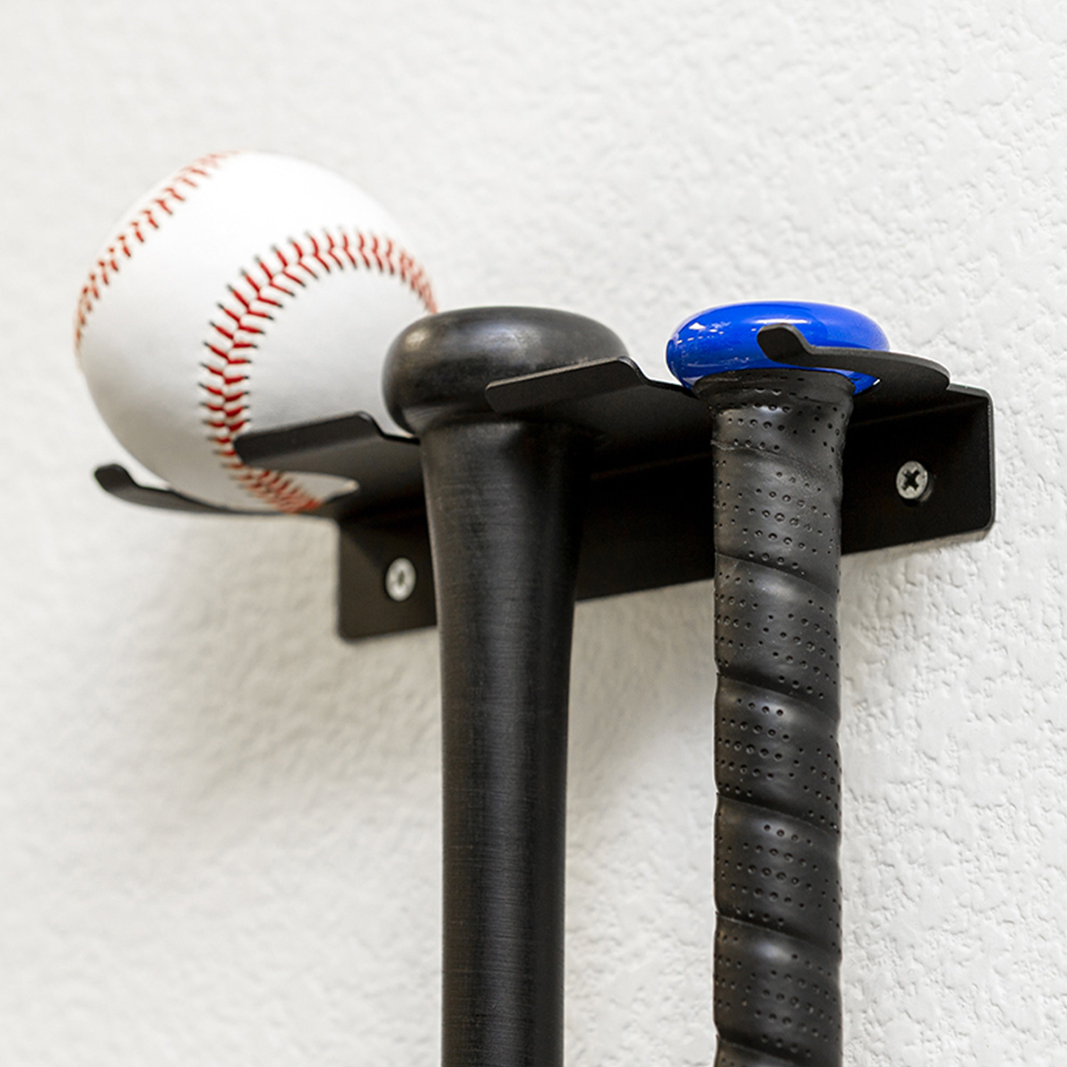 HIDEit Triple Bat Mount hanging in a room with two bats and a baseball.