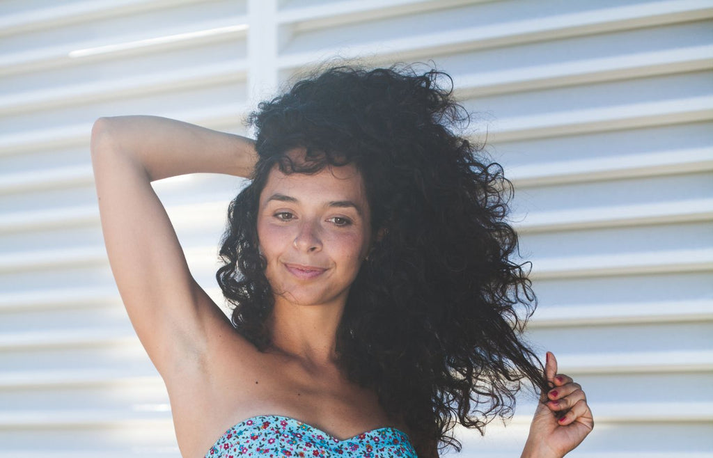 woman smiling and touching her curly hair