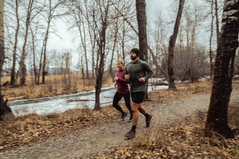 a man and a women running on a wooded trail
