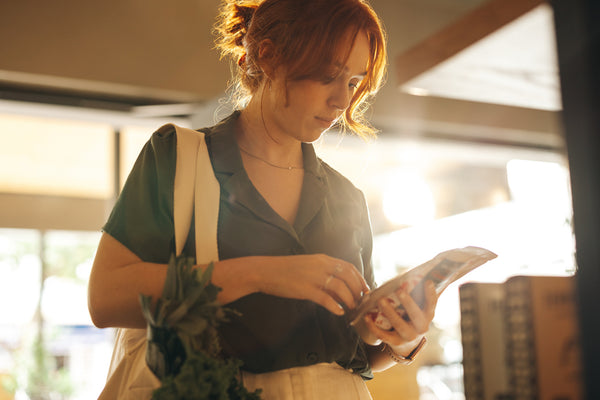 Woman reading the nutrition value of a product to make sure there aren't any refined sugars in it.