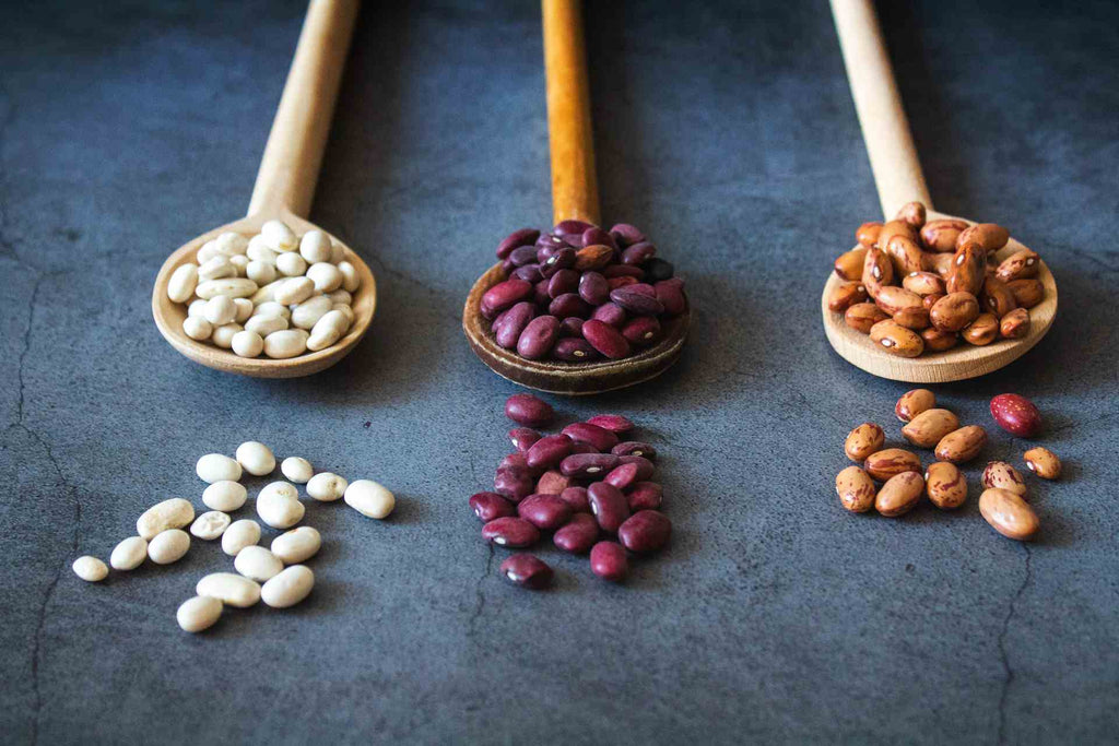 white purple and yellow beans on spoons