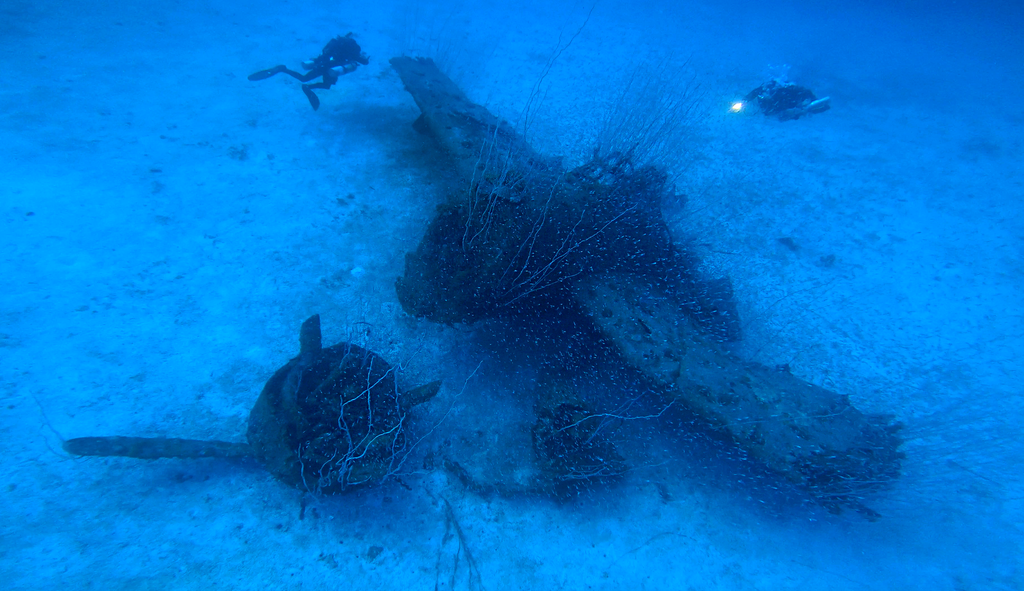 A hellcat plane with divers on the ocean floor in Bikini Atoll