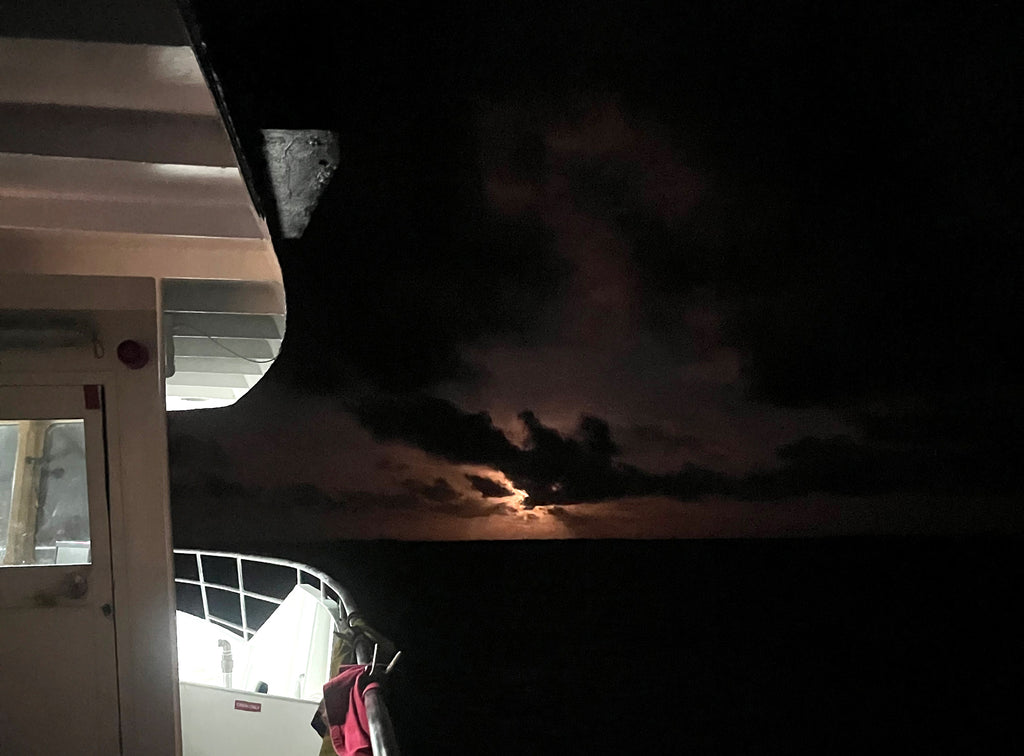 Moon and clouds in night sky seen from the starboard side of a boat