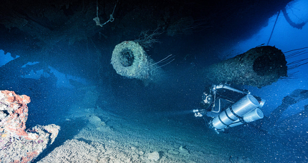 Rebreather diver exploring the twin 16" guns on the upside down Nagato wreck in Bikini Atoll