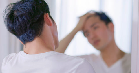 man checking hair in the mirror