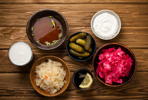 Assorted fermented, probiotic foods on a wood background