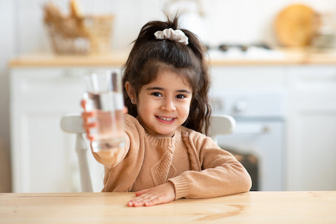 Cute girl holding glass of water toward camera