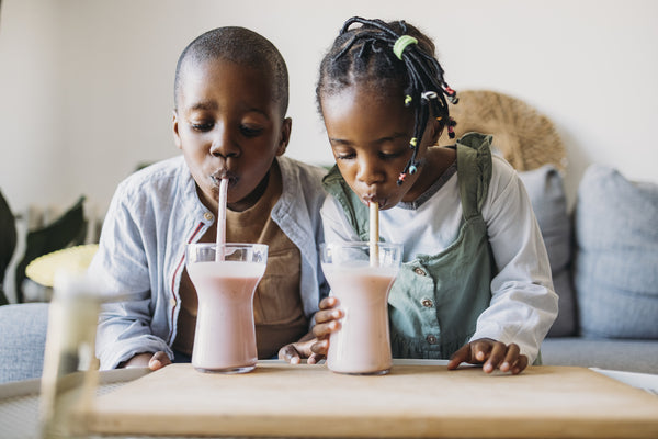 photo of brother and sister sipping prebiotic smoothies through straws