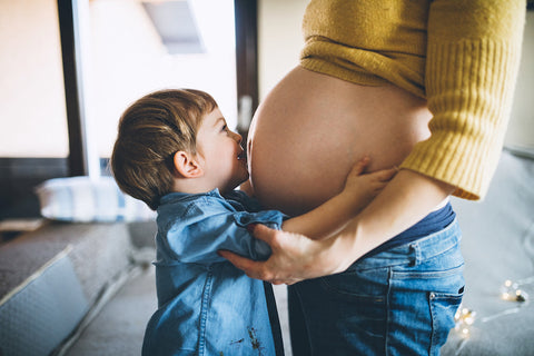 photo of toddler hug and kissing mom's pregnant belly