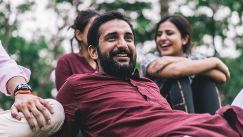 man sitting on grass with friends smiling