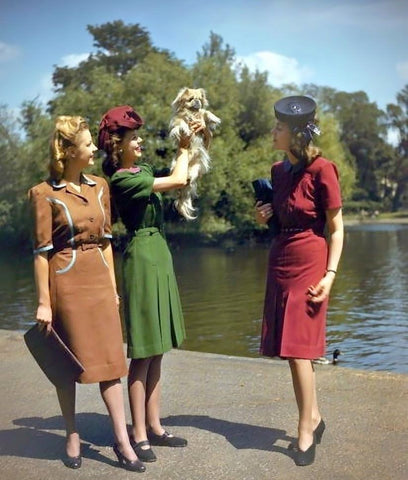 3 women in 1940's dresses one is holding a dog