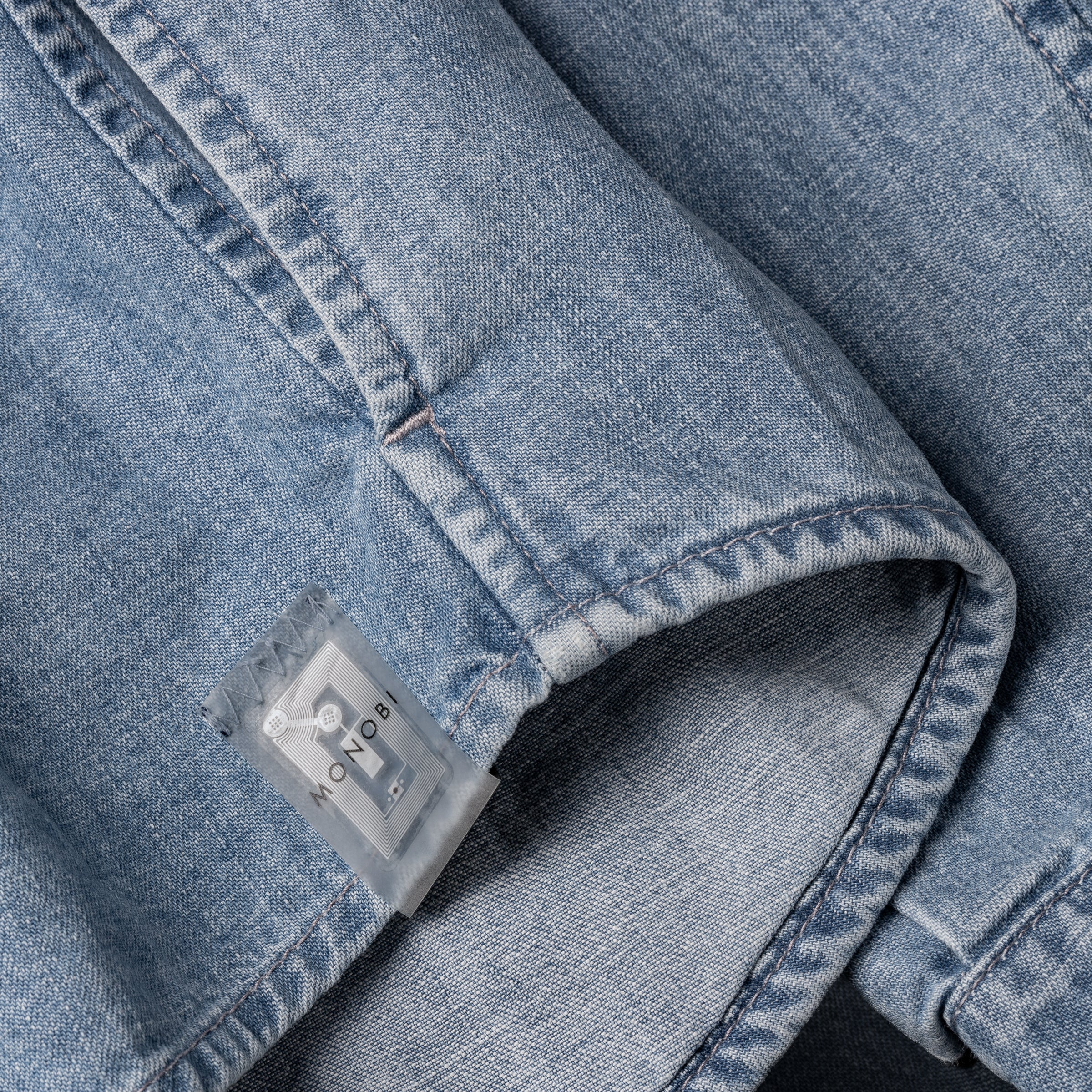 detail of the NFC tag stitched on the bottom of the MONOBI denim shirt