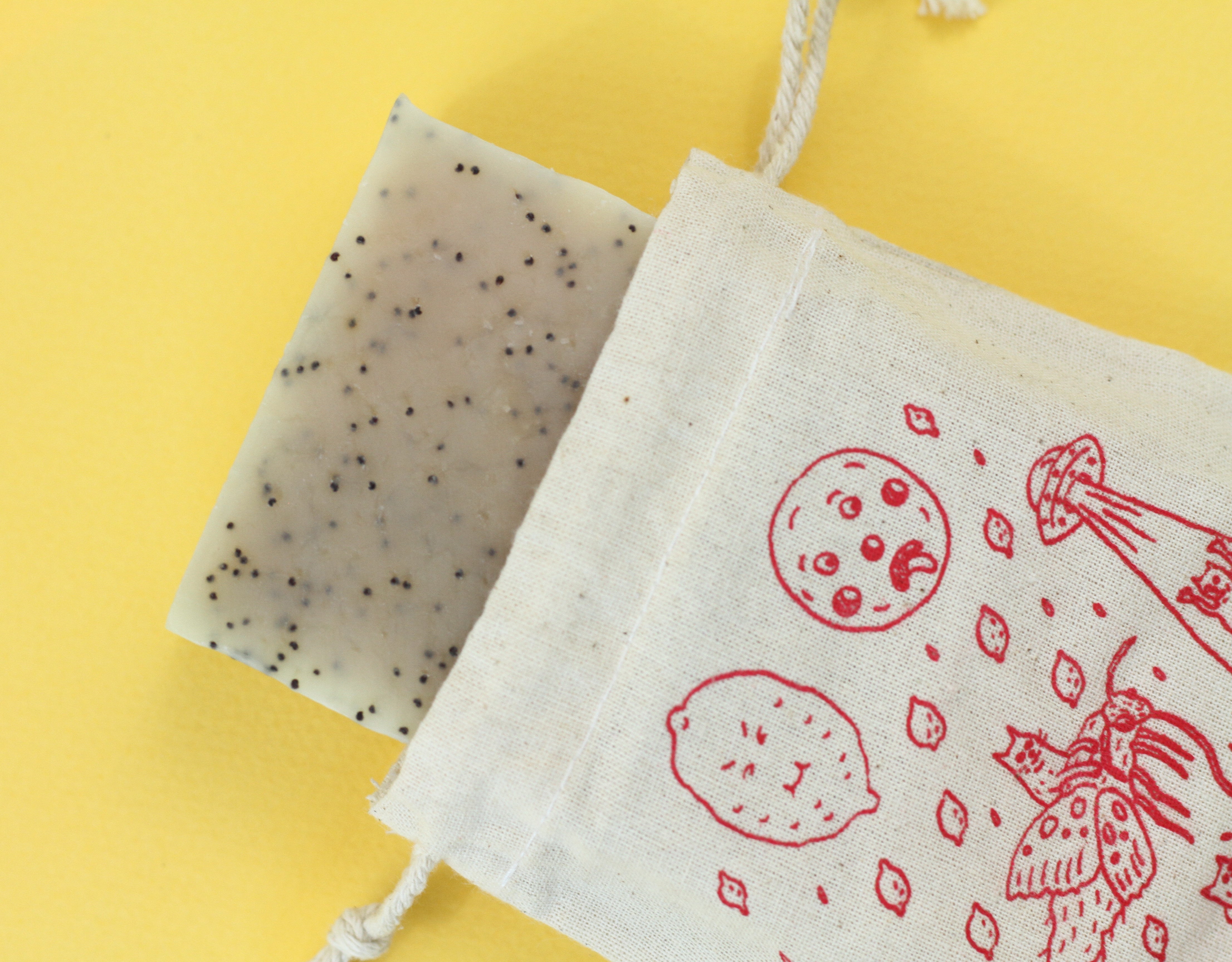 A speckled bar of soap with a canvas bag with a red print