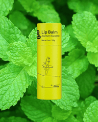 A green tube of lip balm on a background of peppermint plants