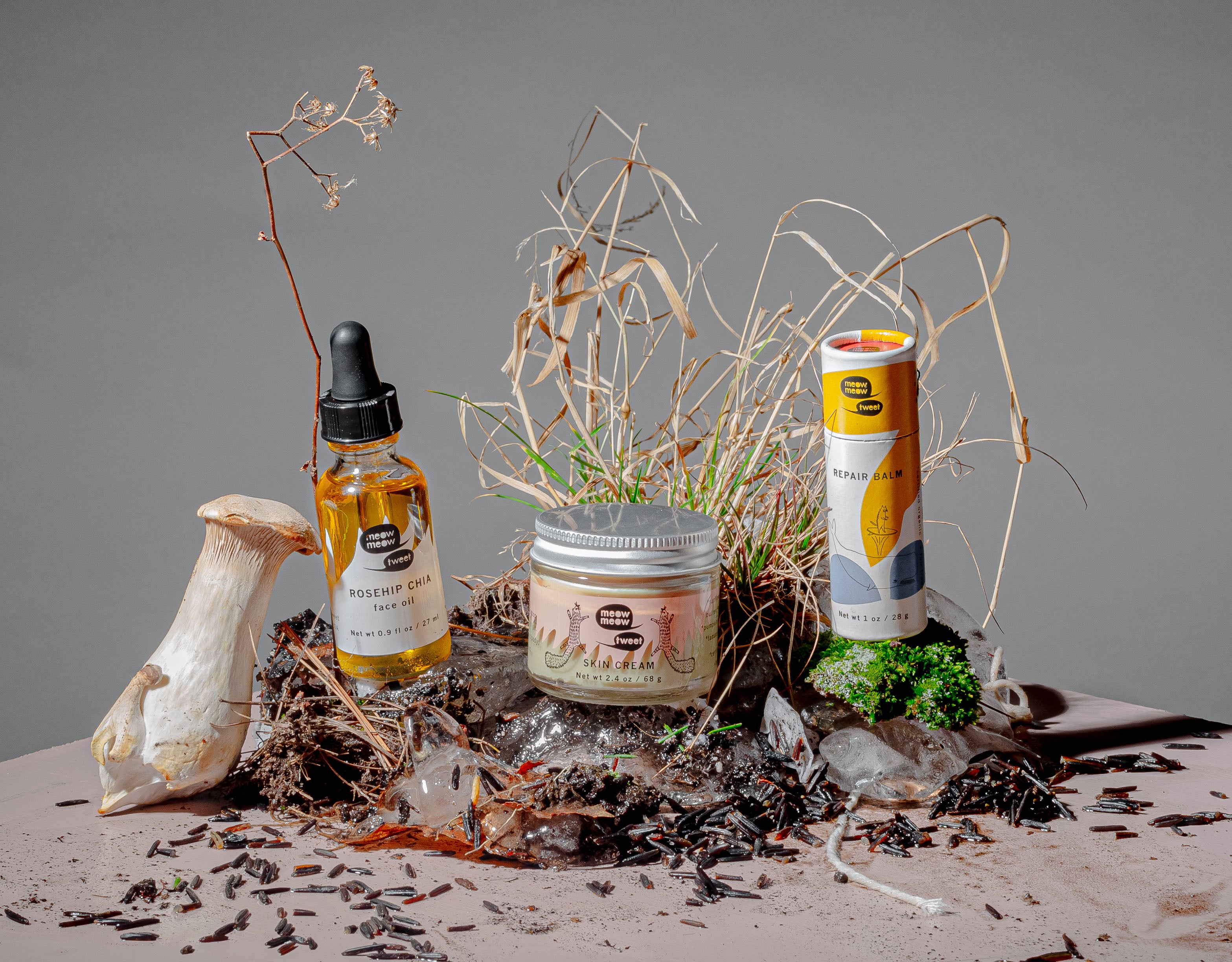 Our skin cream, face oil and repair balm sitting atop a messy pile of ice, mushrooms and dead grass.