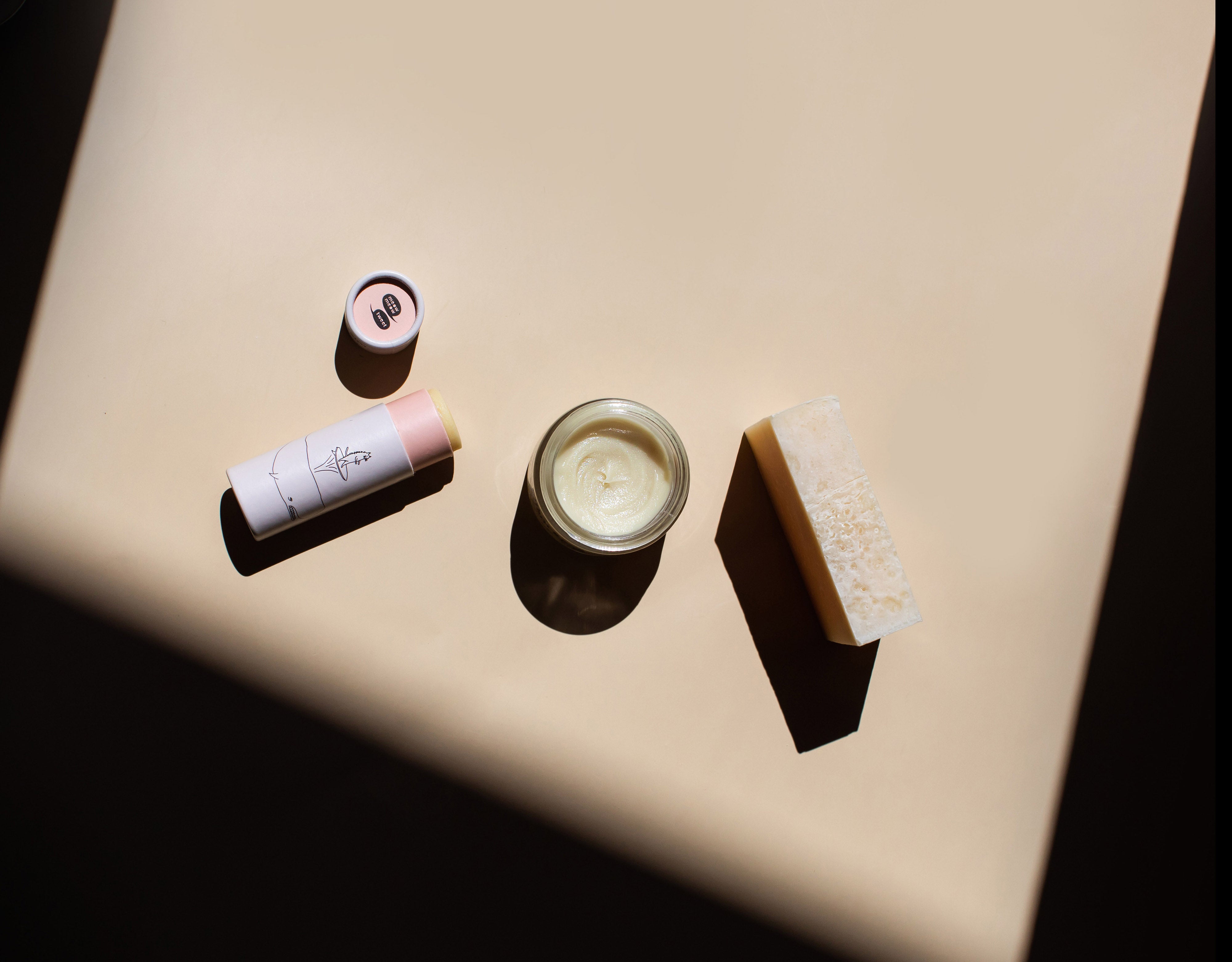 three tan colored products sit in a dramatic shadow on a tan table