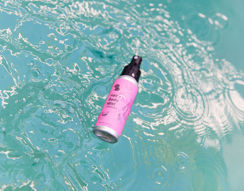 A pink bottle floats in turquoise blue pool water