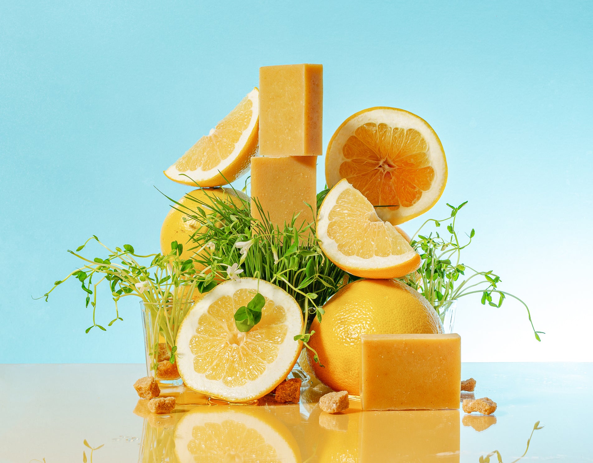 a tall stack of yuzu soap, yuzu slices and herbs on a sky blue background