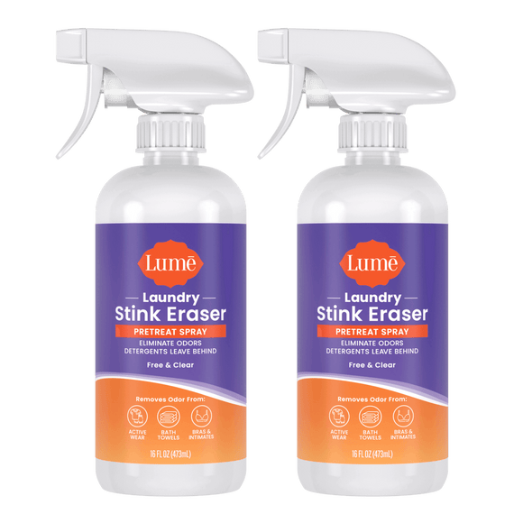 Two purple and orange bottles of Laundry Stink Eraser Pretreat Spray with a white spray trigger top. The text on the label reads "eliminate odors detergents leave behind. Free & clear. Removes odor from:" with icons indicating activewear, bath towels, and bras and intimates.