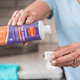 A woman pouring a capful of detergent booster