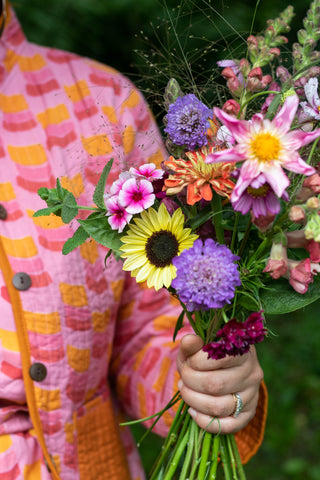 Sarah holds a bouquet of flowers wearing a Citrus Segment Quilted Jacket 