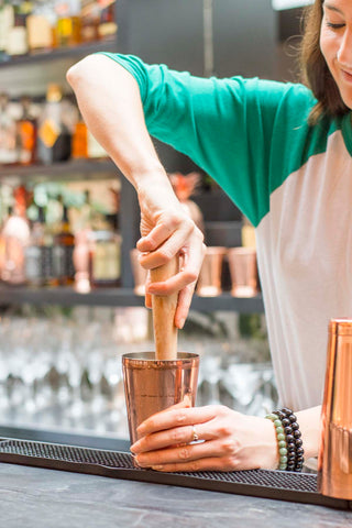 bartender muddling ingredients in shaker