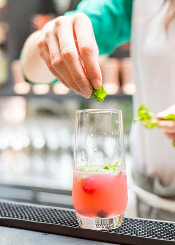 bartender adding mint to crimson berry mojito