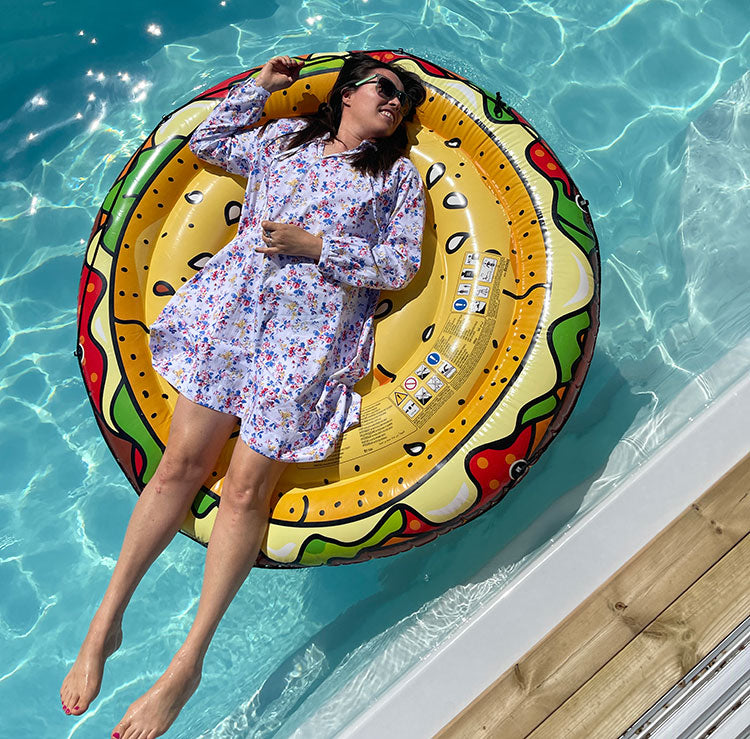 A woman wears a floral dress while laying on an inflatable in a pool