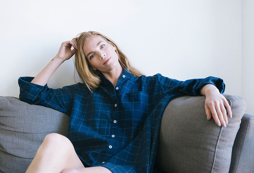 Placket Sleep Shirt in Navy Windowpane on model sitting on sofa. 